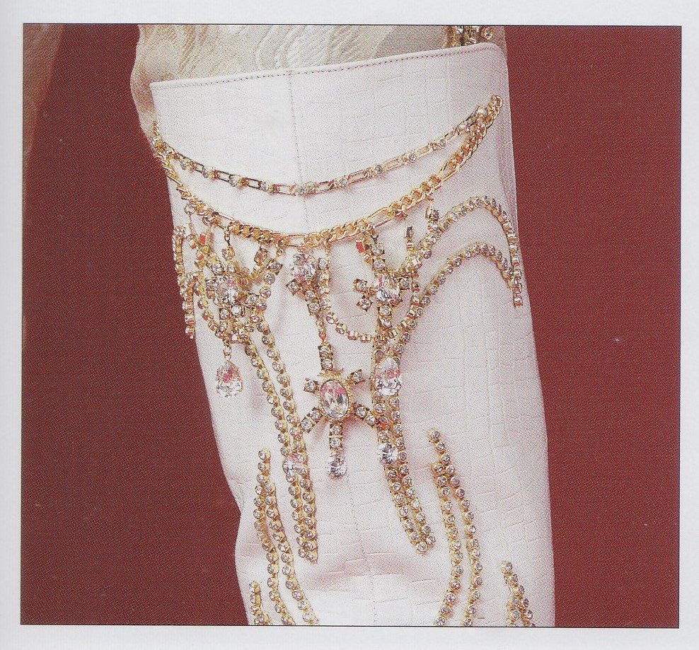 A closeup of the top of Kiriya Hiromu's white boots with crystal and gold chain accents in curving patterns.