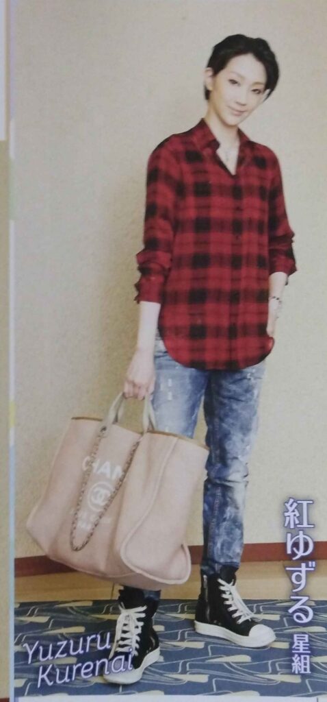 Kurenai Yuzuru wearing a red and black flannel shirt, distressed jeans, and black sneakers, and holding an oversized Chanel tote.