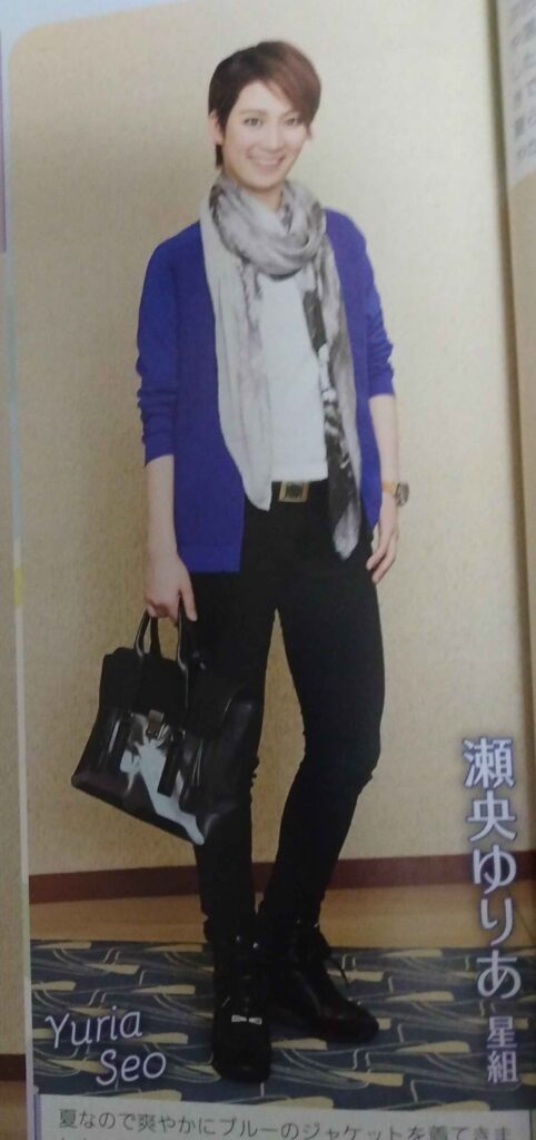 Seo Yuria wearing blue jacket, white shirt, black pants, and black shoes, with loose gray scarf and black purse.